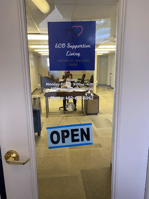 Glass door shows ECO Supportive Living interior with staff at a desk and an OPEN sign.