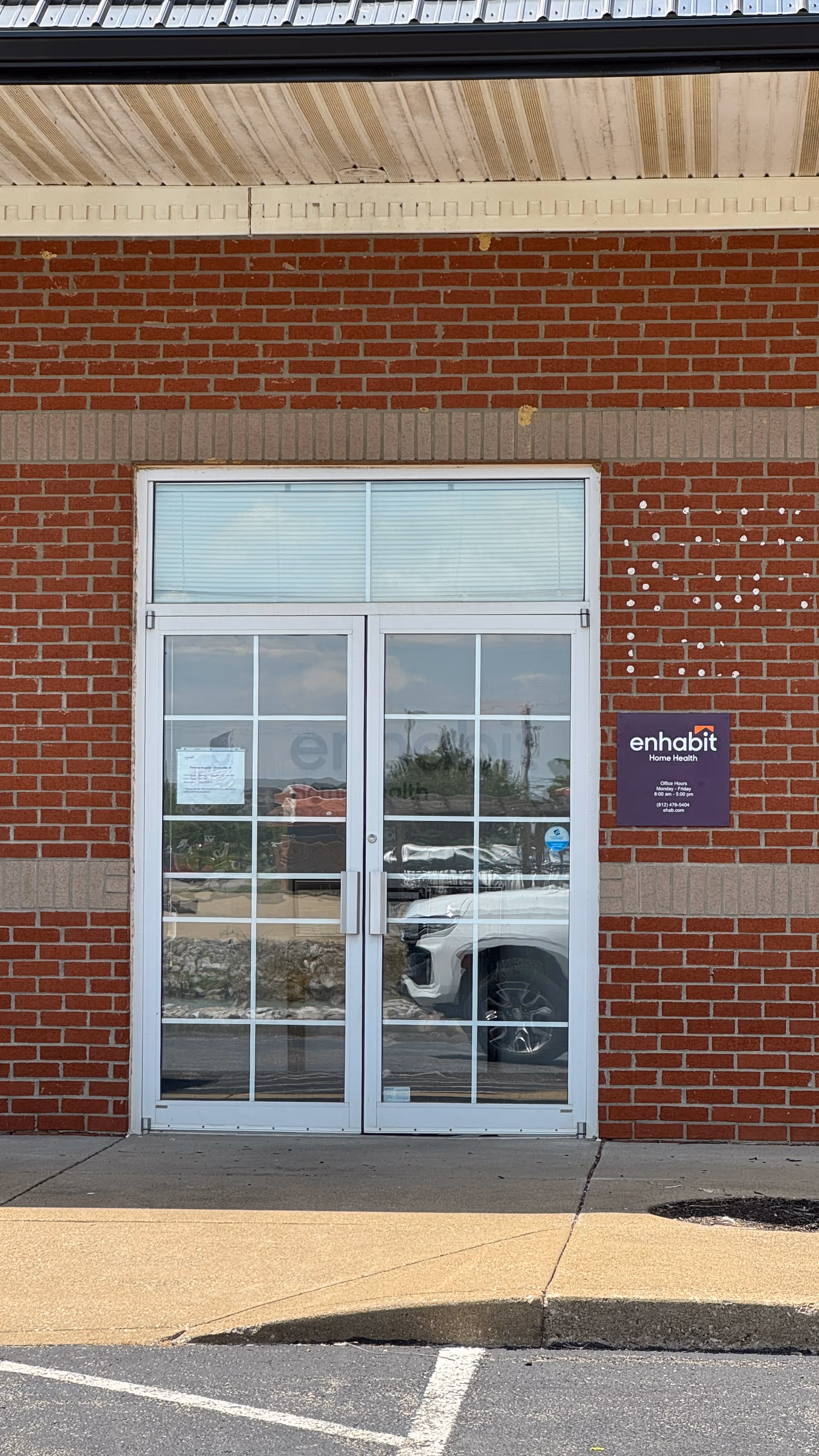 Exterior brick facade with double glass doors and Enhabit sign.