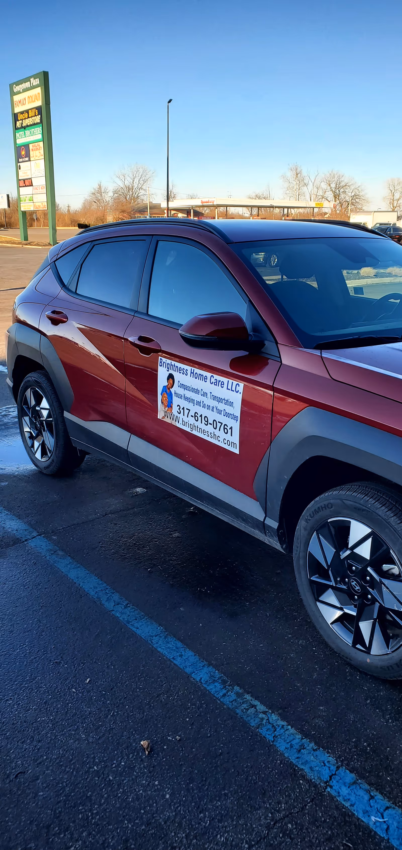 Maroon SUV in a parking lot displaying Brightness Home Care LLC advertisement on the door.