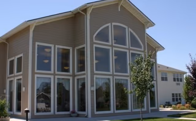 Modern two-story senior living facility with large arched windows and beige siding.
