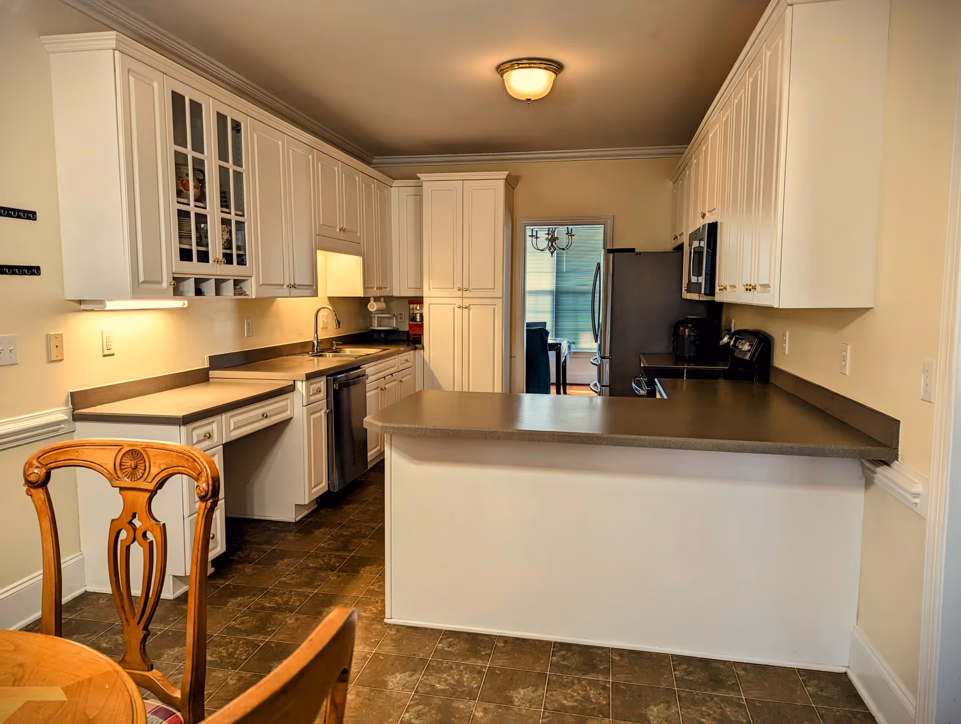 Bright, white kitchen with countertops, cabinets, sink, and appliances in a senior living facility.