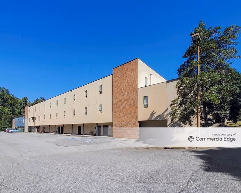 Exterior view of a beige senior living facility with brick accents and parking.