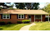 Front view of a single-story brick retirement home with a curved walkway and manicured lawn.
