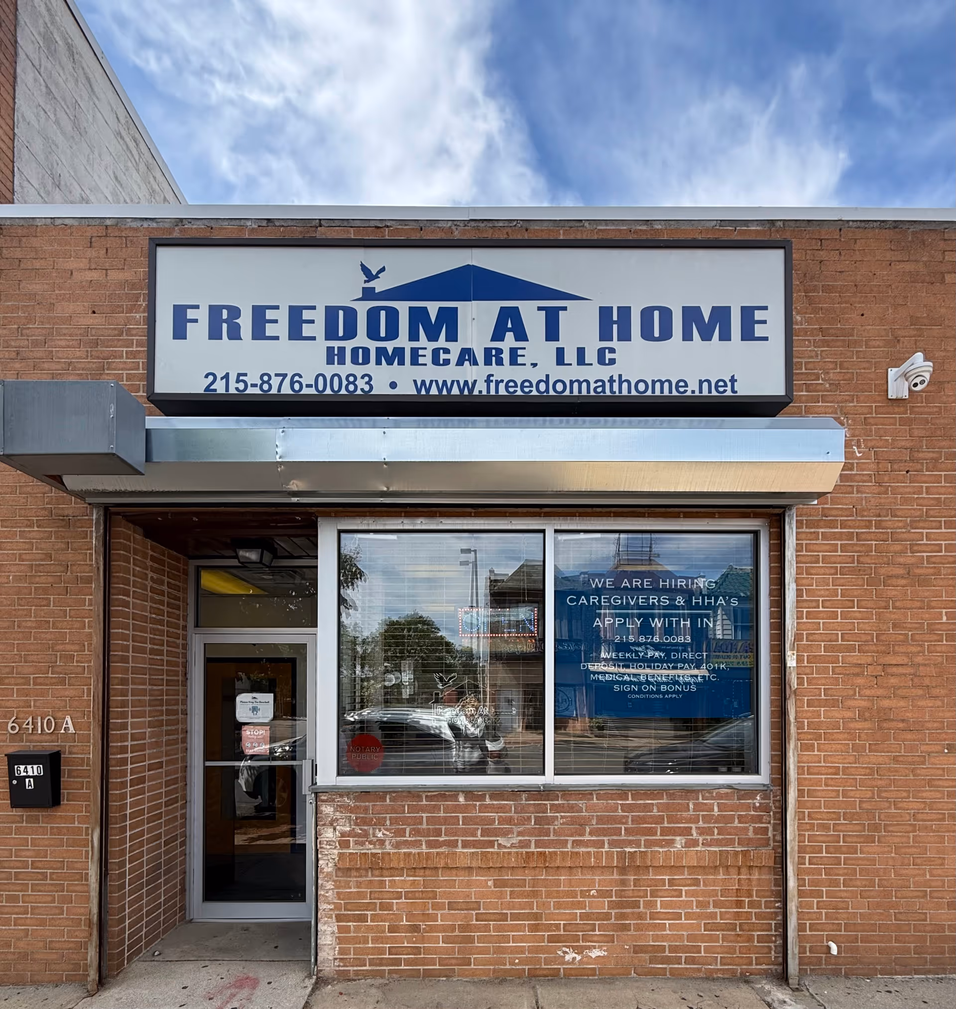 Brick building exterior with a large Freedom At Home HomeCare sign above entrance.