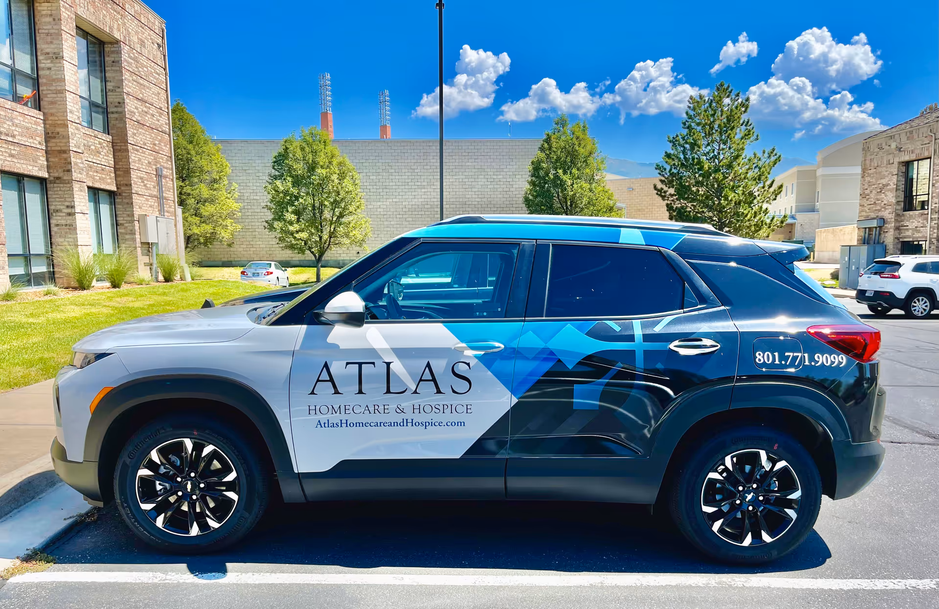 Atlas Homecare and Hospice vehicle parked outside a modern building on a sunny day.