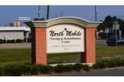 A brick and white sign for North Mobile Nursing & Rehabilitation Center on a grassy lot.