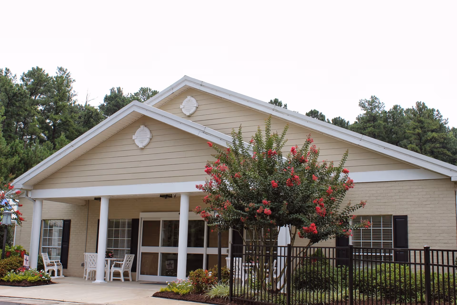 Front view of Seasons at Southpoint memory care building with a porch and flowering tree.