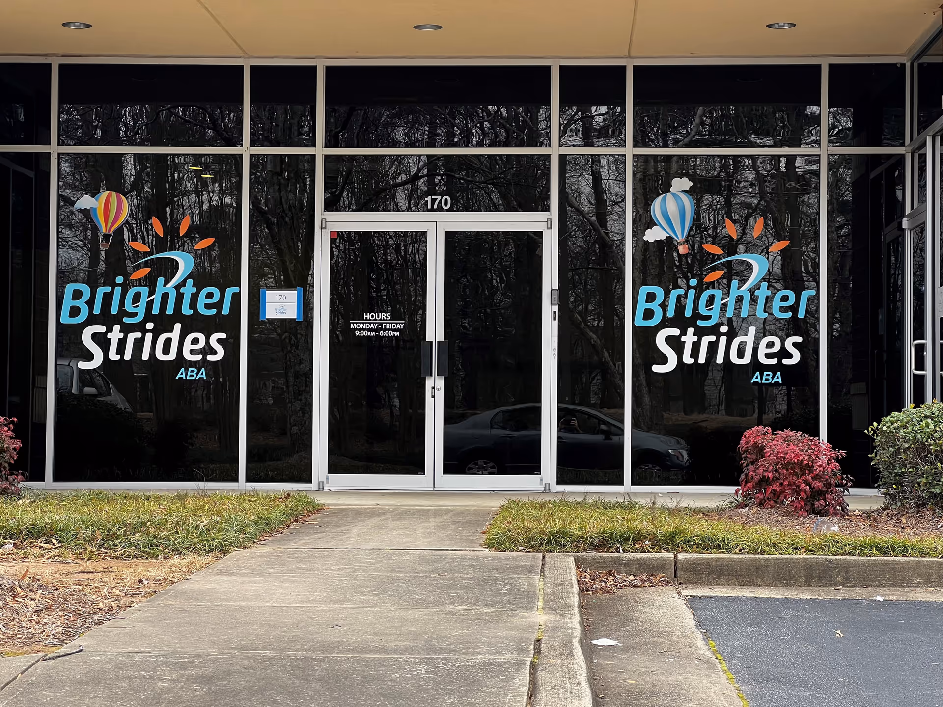 Glass storefront displaying Brighter Strides ABA Therapy logos, with central entrance door.