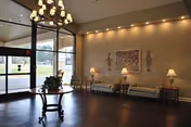 Senior living facility lobby with chandelier, seating area, and glass entrance doors.