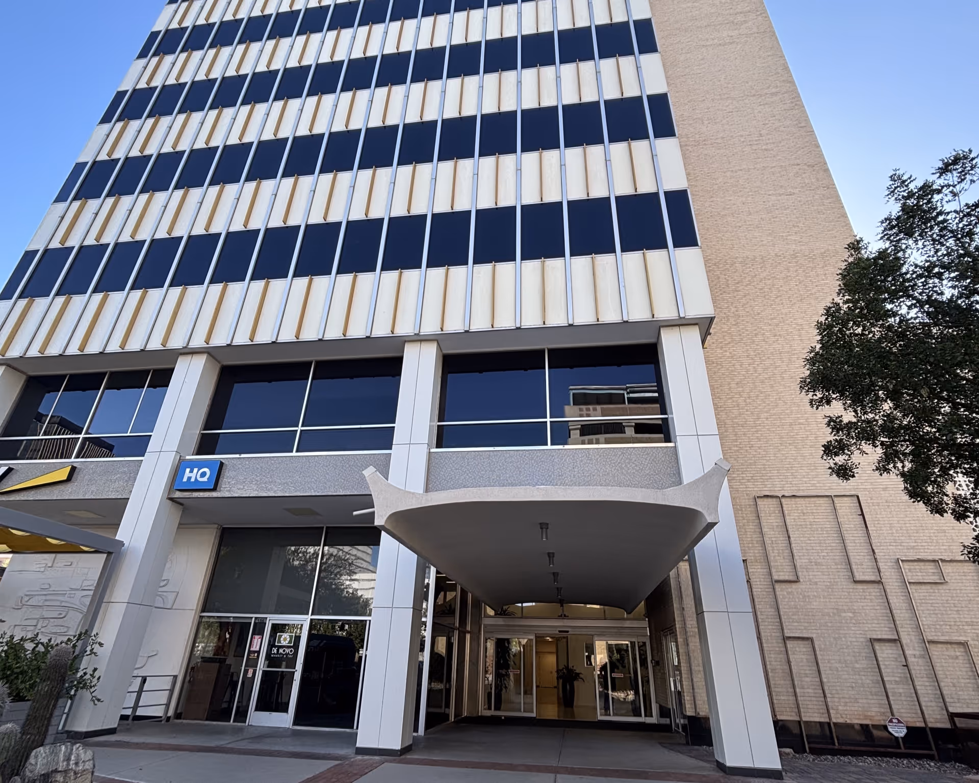 Tall modern building exterior with glass doors and a curved entrance canopy.