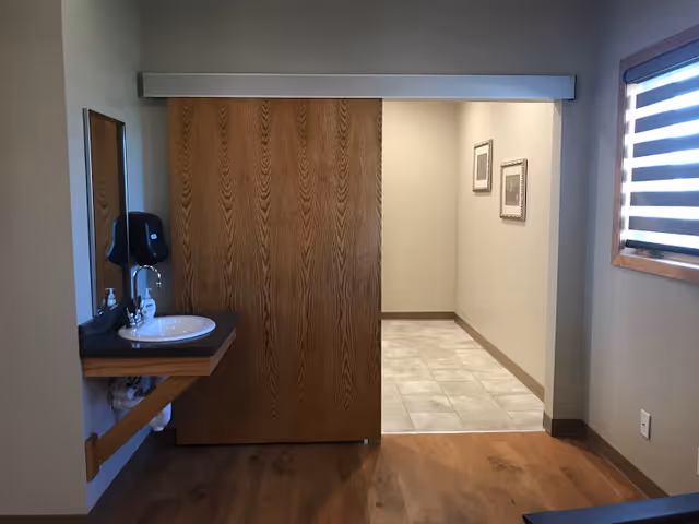 Interior view of a small bathroom area with sink, mirror, and partition.