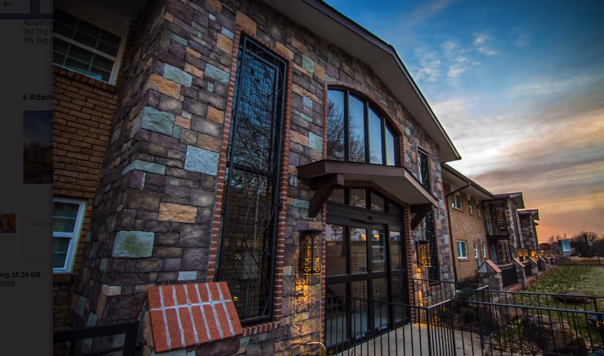 Stone facade building exterior with arched windows and glass entrance at sunset.