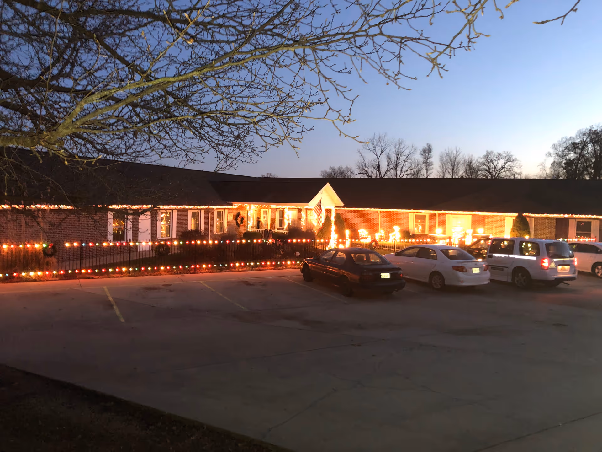 Shepherds View Assisted Living front adorned with festive Christmas lights and parked cars.