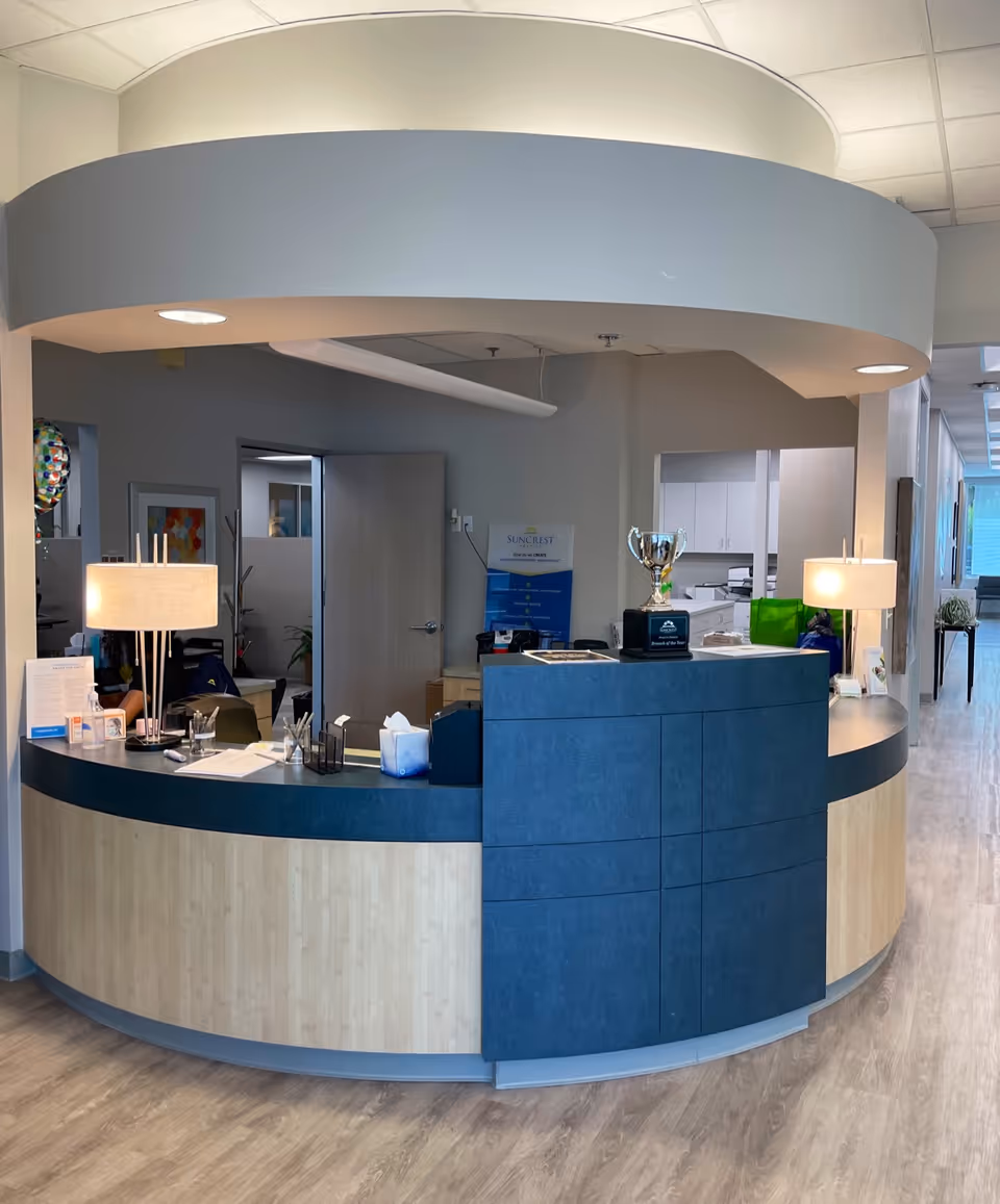 Curved reception desk in Suncrest Hospice lobby with lamps and a trophy.