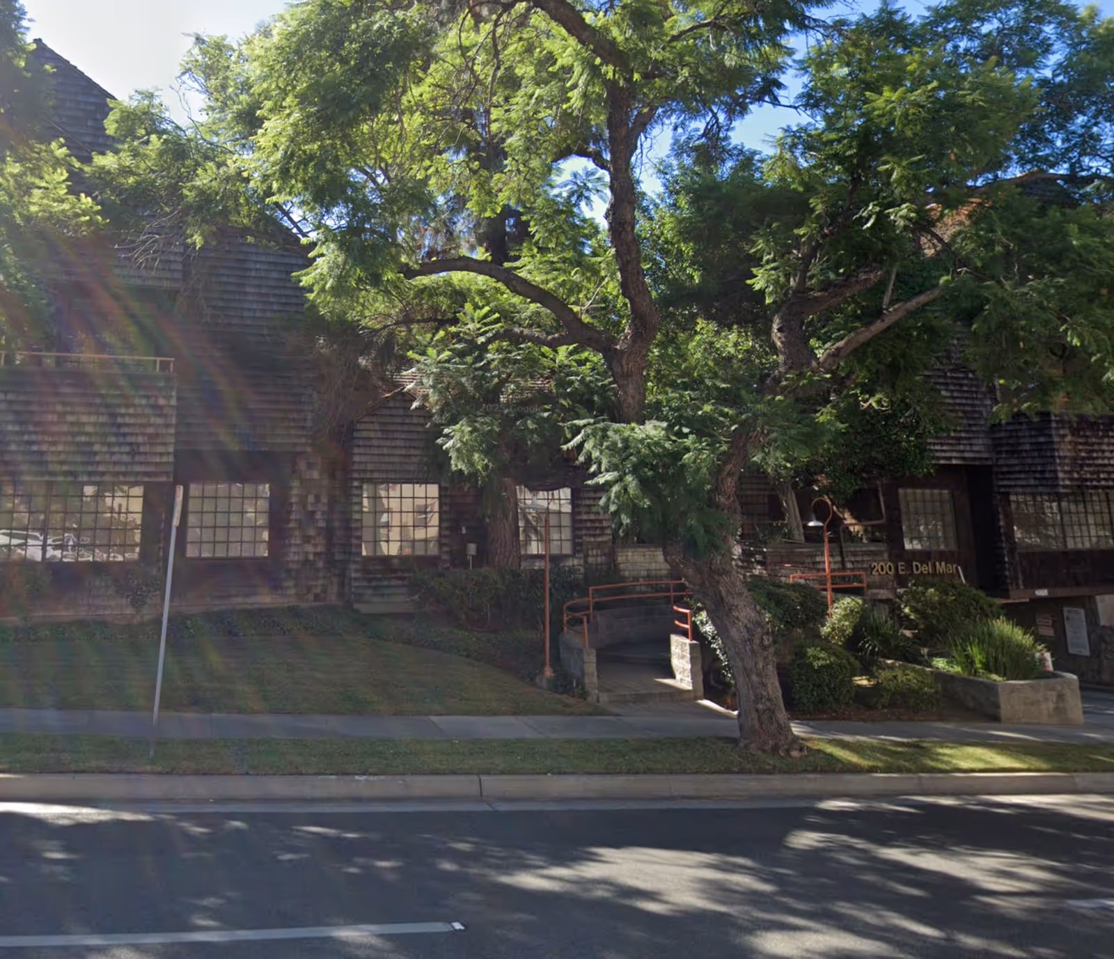 Exterior view of a brick building with large trees along a sidewalk