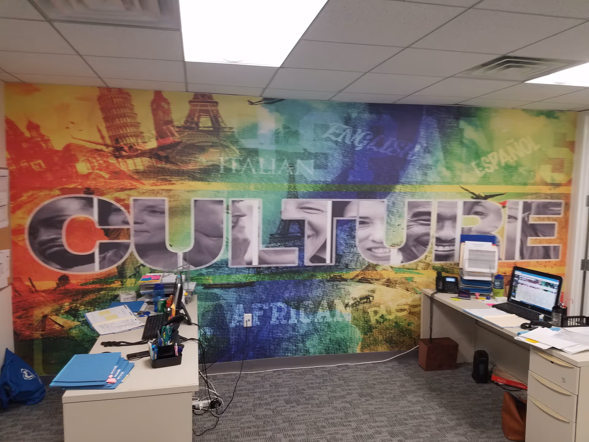 Colorful mural with the word CULTURE on an office wall, desks, and computers.