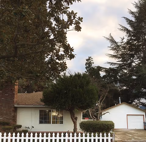 Front view of Pinehill Residential Care, a single-story building with a white picket fence.
