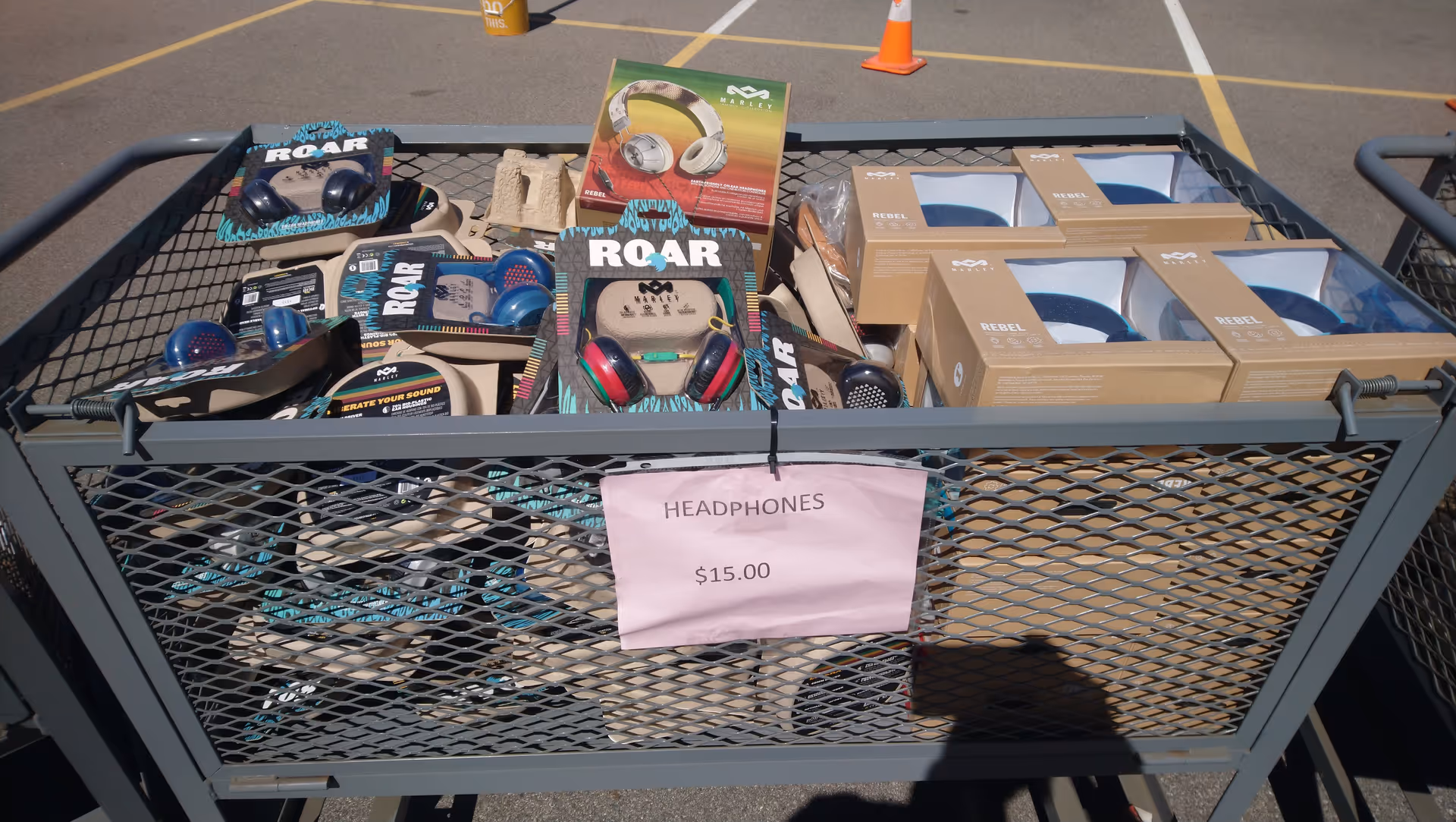 Cart filled with headphones and boxed items; pink sign reads HEADPHONES $15.00