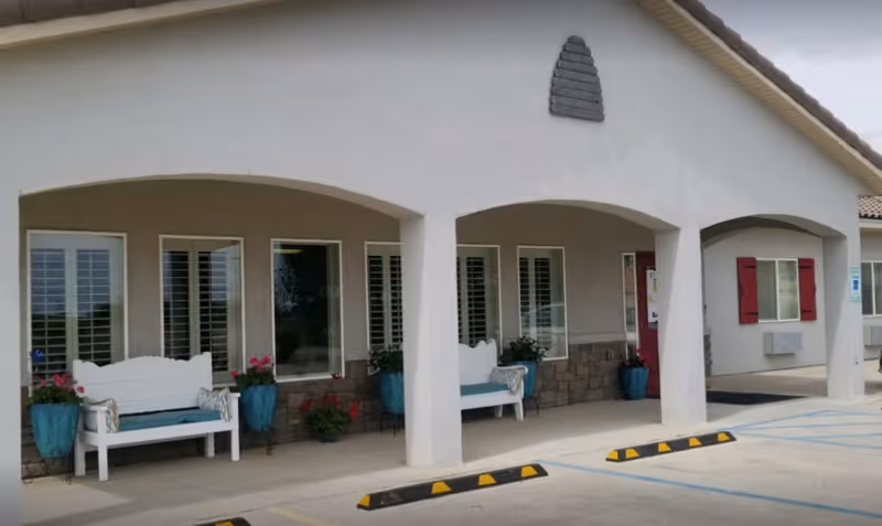 BeeHive Homes Hobbs exterior with arched porch, white benches, and potted plants along the front.