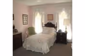 Bedroom with a white bed, two nightstands, lamps, and pastel pink walls.