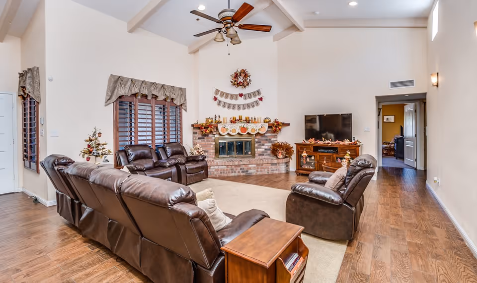 Bright living room with leather recliners arranged around a brick fireplace and TV, decorated for fall.