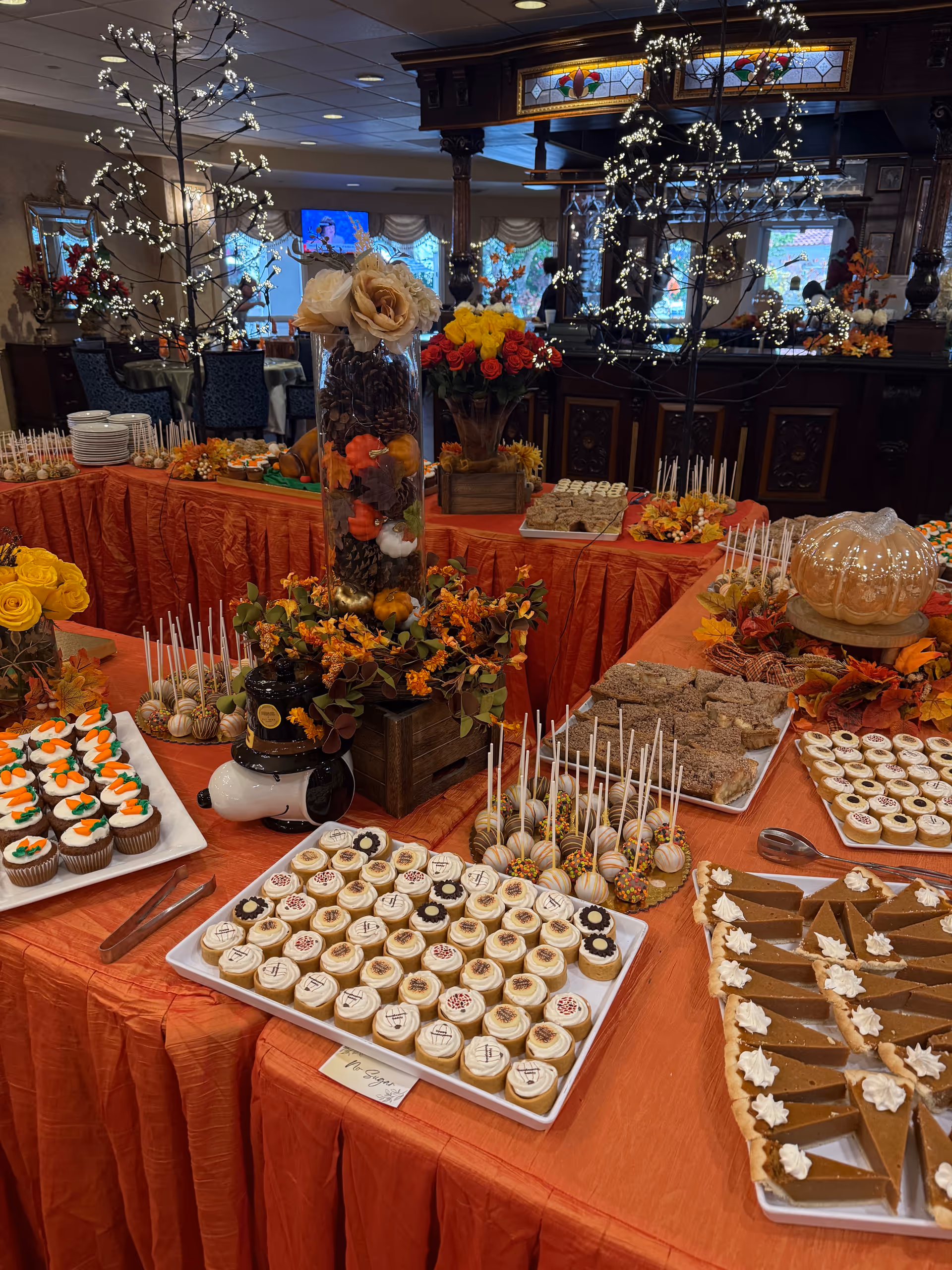 Elaborate dessert spread on orange-draped tables in a formal dining room.
