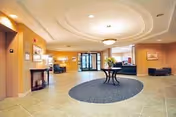 Covenant Village lobby with circular ceiling light, central round rug table, and seating.