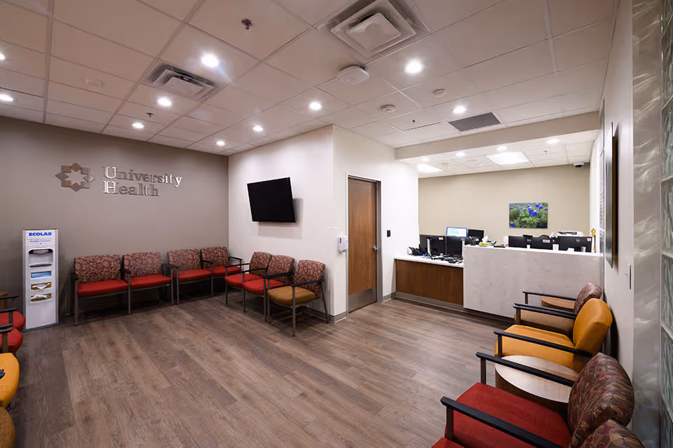 Waiting area with red chairs, a reception desk, and wall-mounted TV.