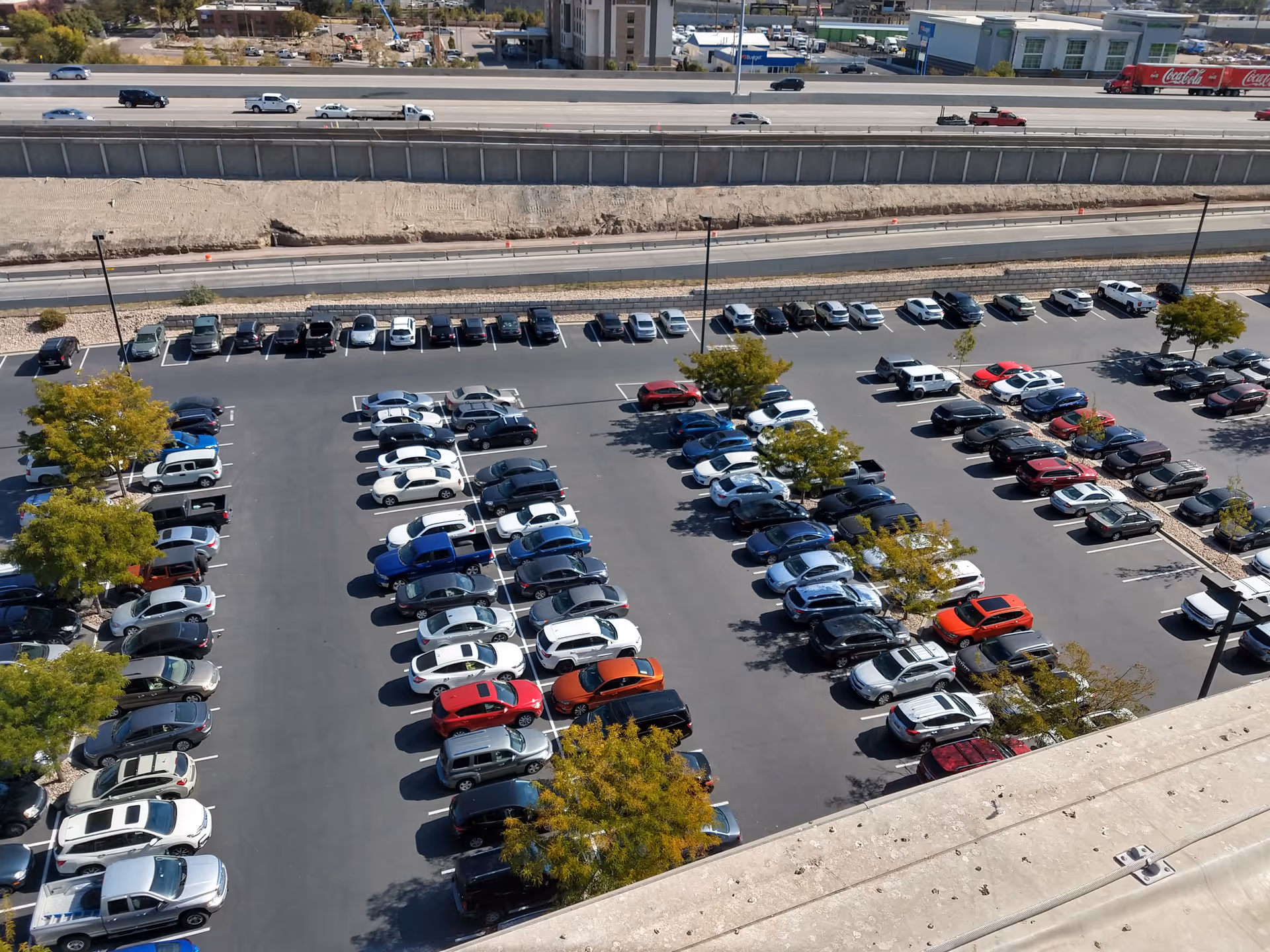 Aerial view of a large parking lot with numerous cars beside a highway.