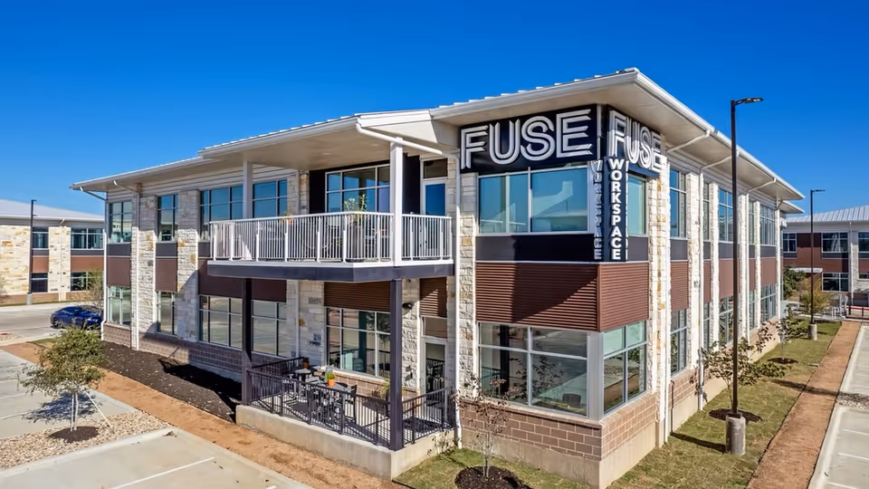 Two-story modern building exterior with stone accents and large glass windows.
