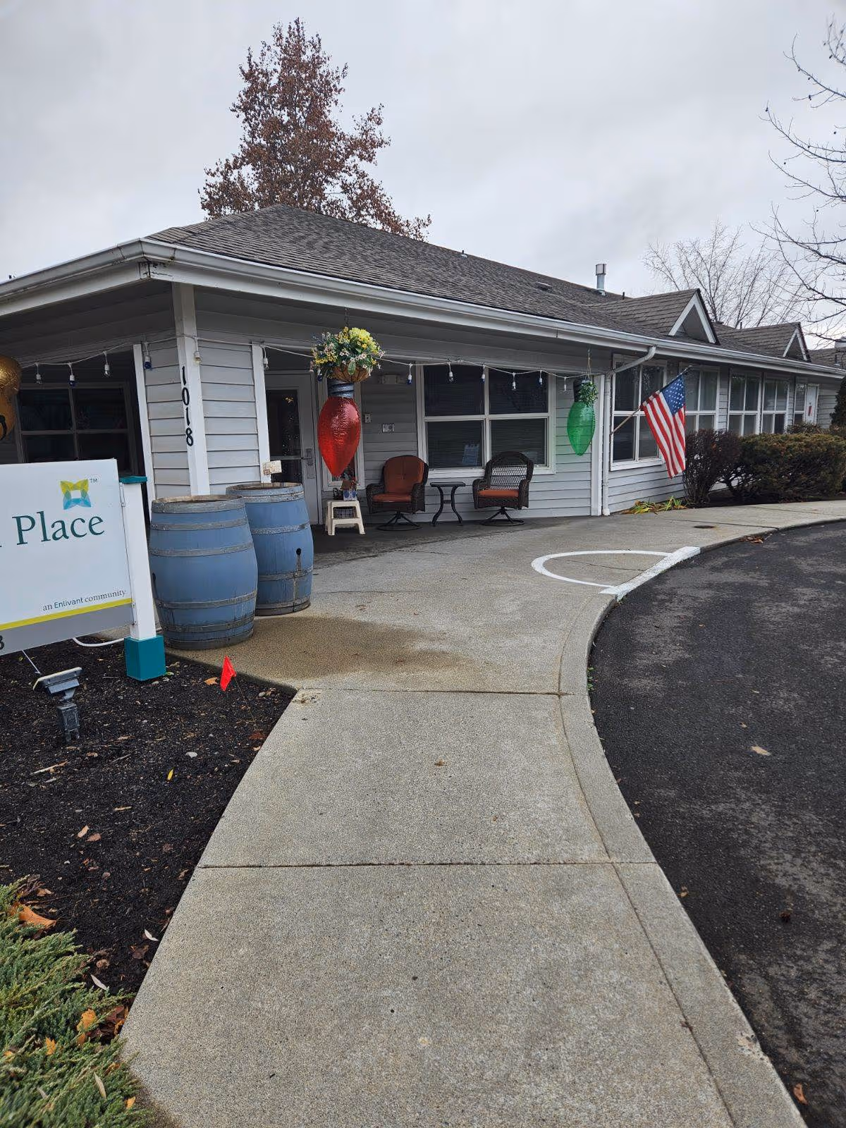 Exterior view of Trustwell Living at Whitman Place showing a porch with chairs and American flag