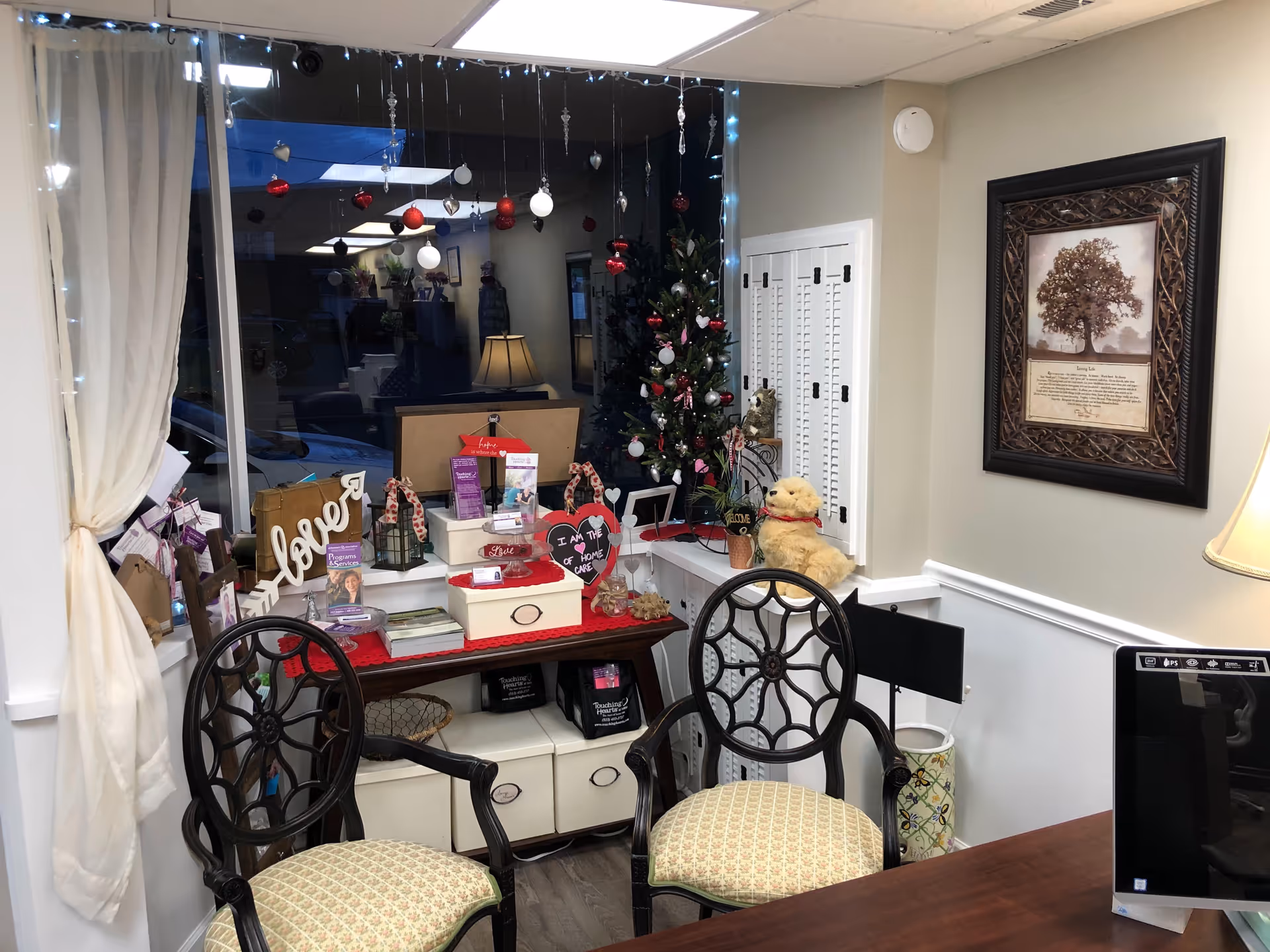 Decorated indoor lounge with Christmas tree, gifts, and ornate chairs.