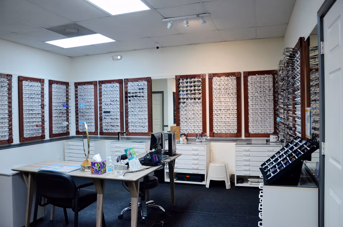 Eyewear showroom inside a facility with wall displays of frames and a desk.