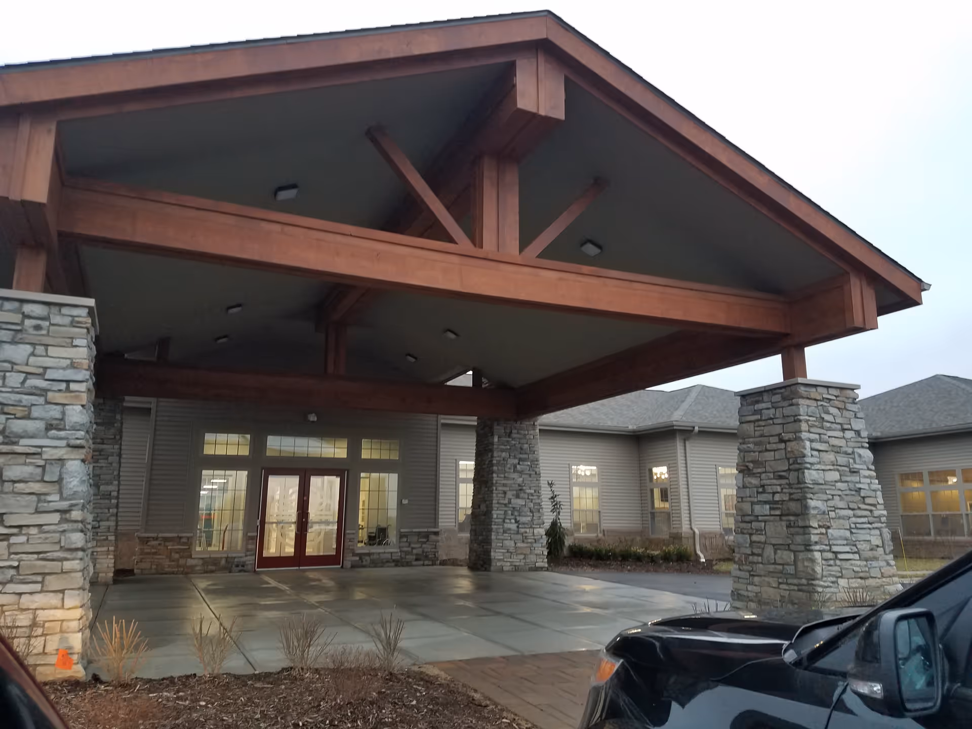 Wood-framed porte-cochère over a glass double door entrance.