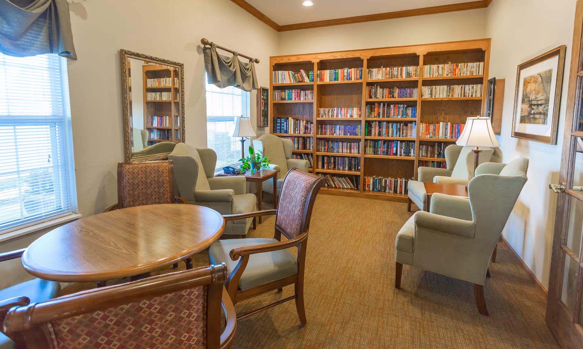 Brookdale Dodge City library lounge with tall bookshelves, seating, and a round table.