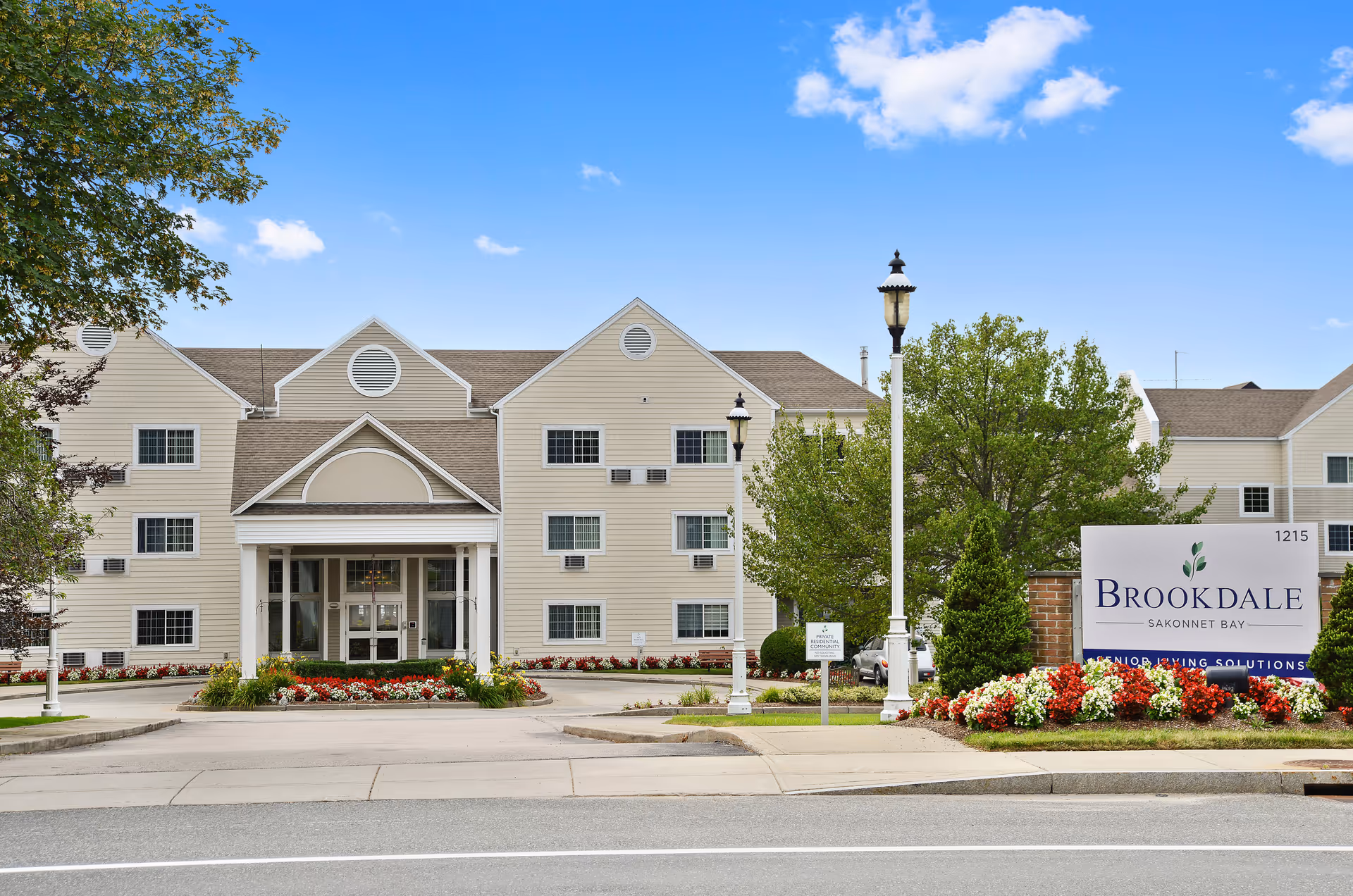 Exterior view of Brookdale Sakonnet Bay facility with entrance, sign, and landscaping.