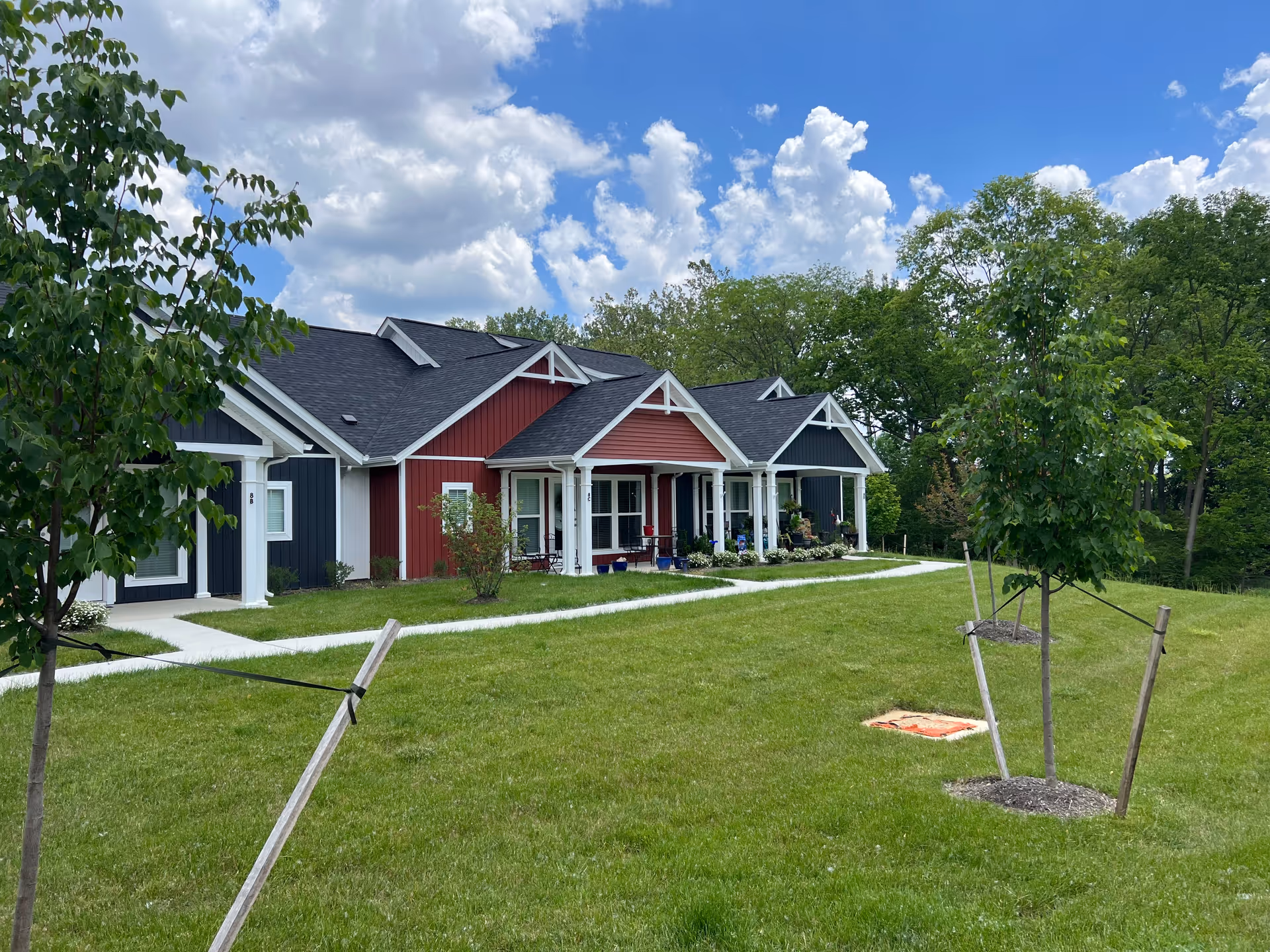 Row of colorful, single-story cottages with porches along a green lawn.