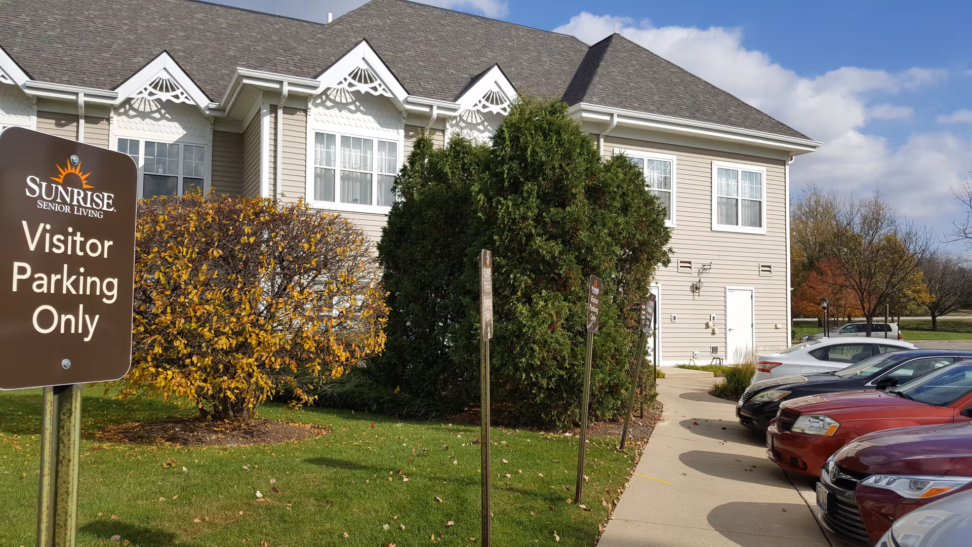 Exterior view of Sunrise of Palos Park senior living building with visitor parking sign.