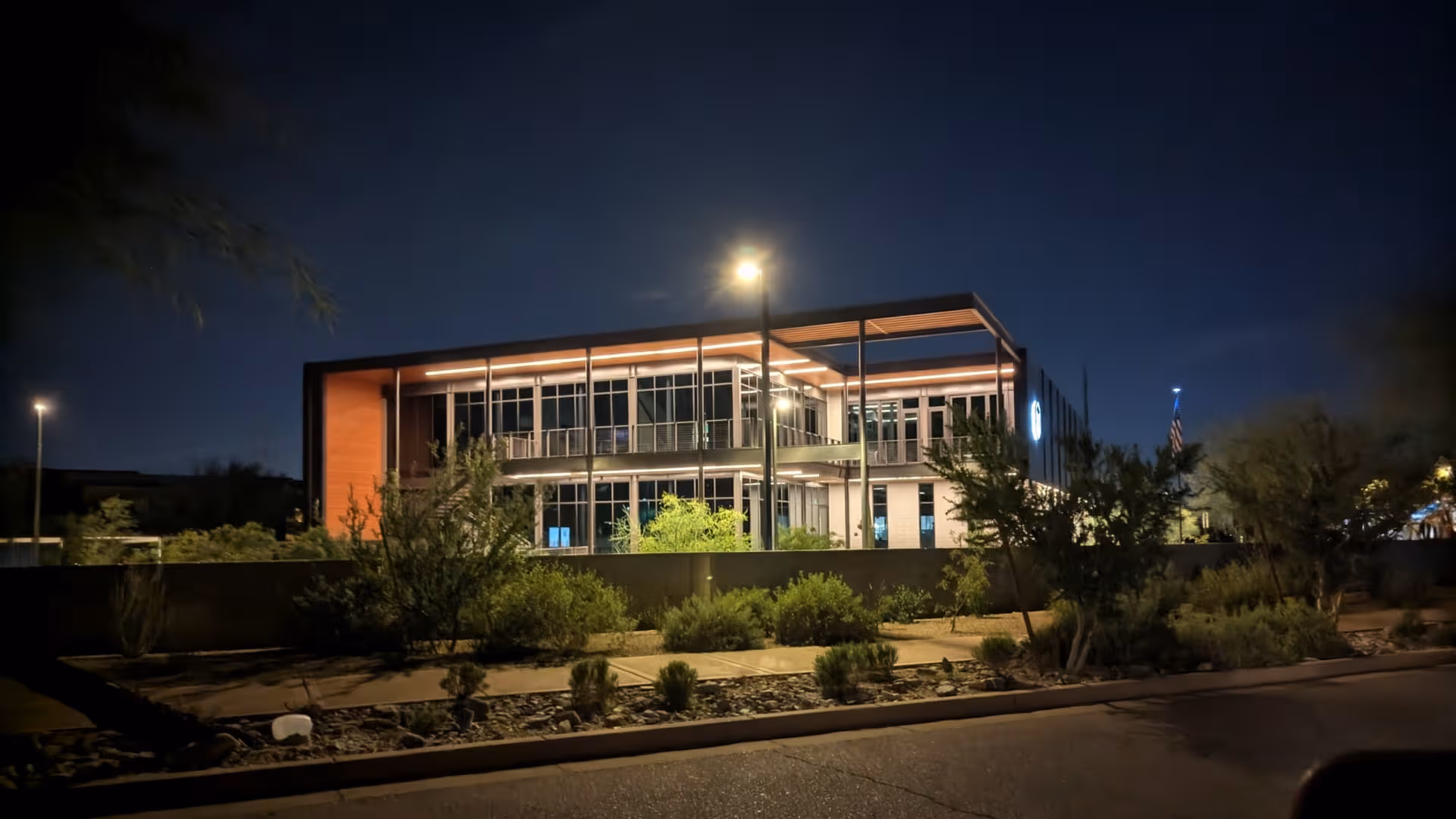 Night exterior of Santé of North Scottsdale, a modern two-story senior living facility, with desert landscaping.
