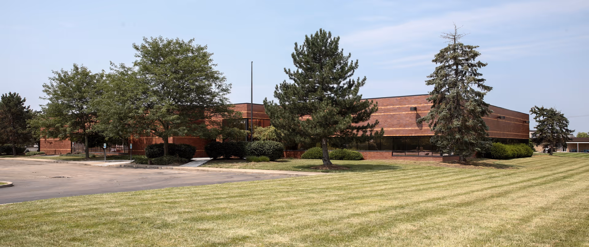 A brick Council On Aging building sits among trees with a grassy foreground.