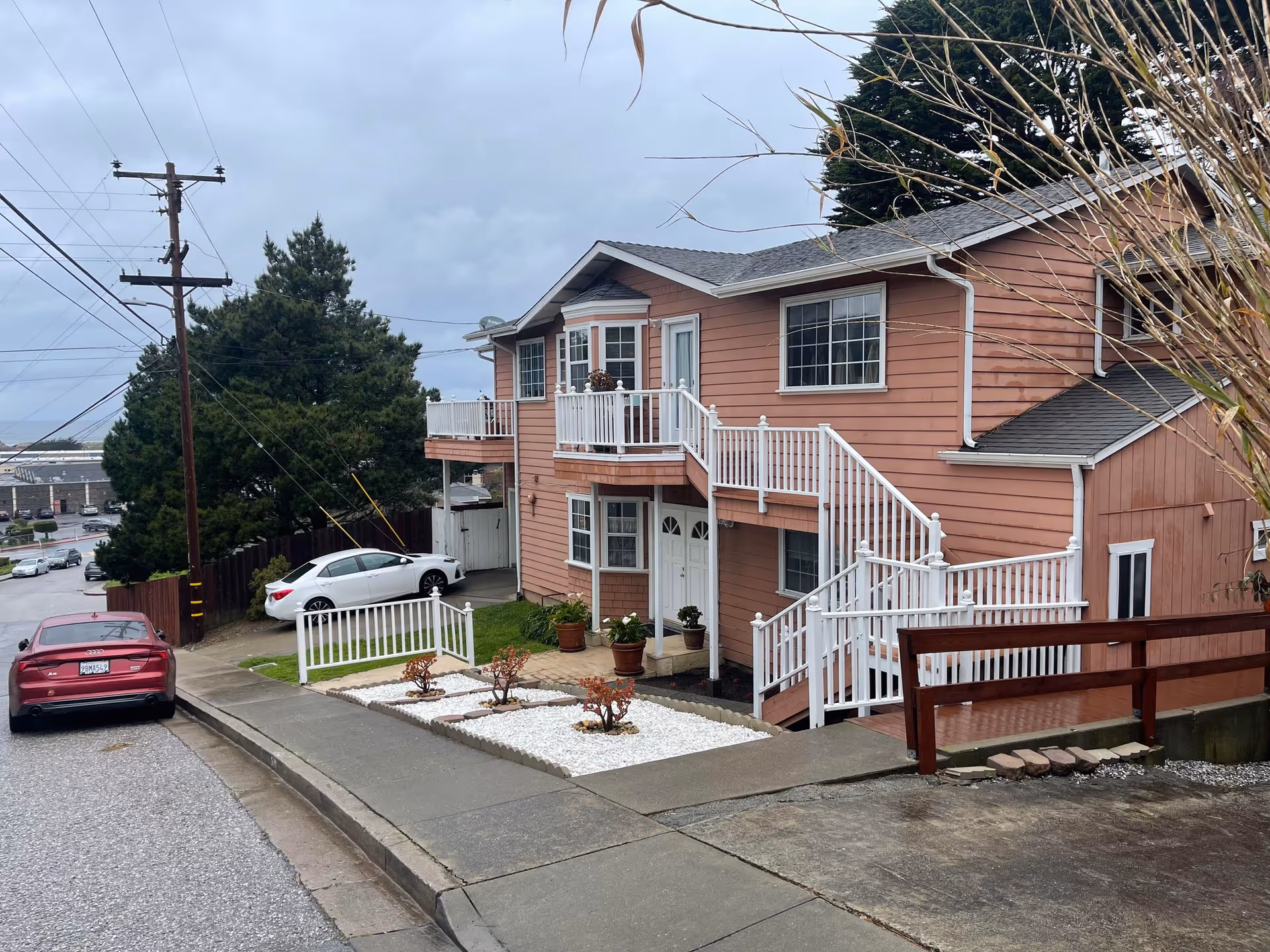 Exterior view of TLC Pacifica's two-story pink building with white railings and stairs.