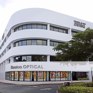 White curved facade building exterior with Sutton Optical storefront on ground level