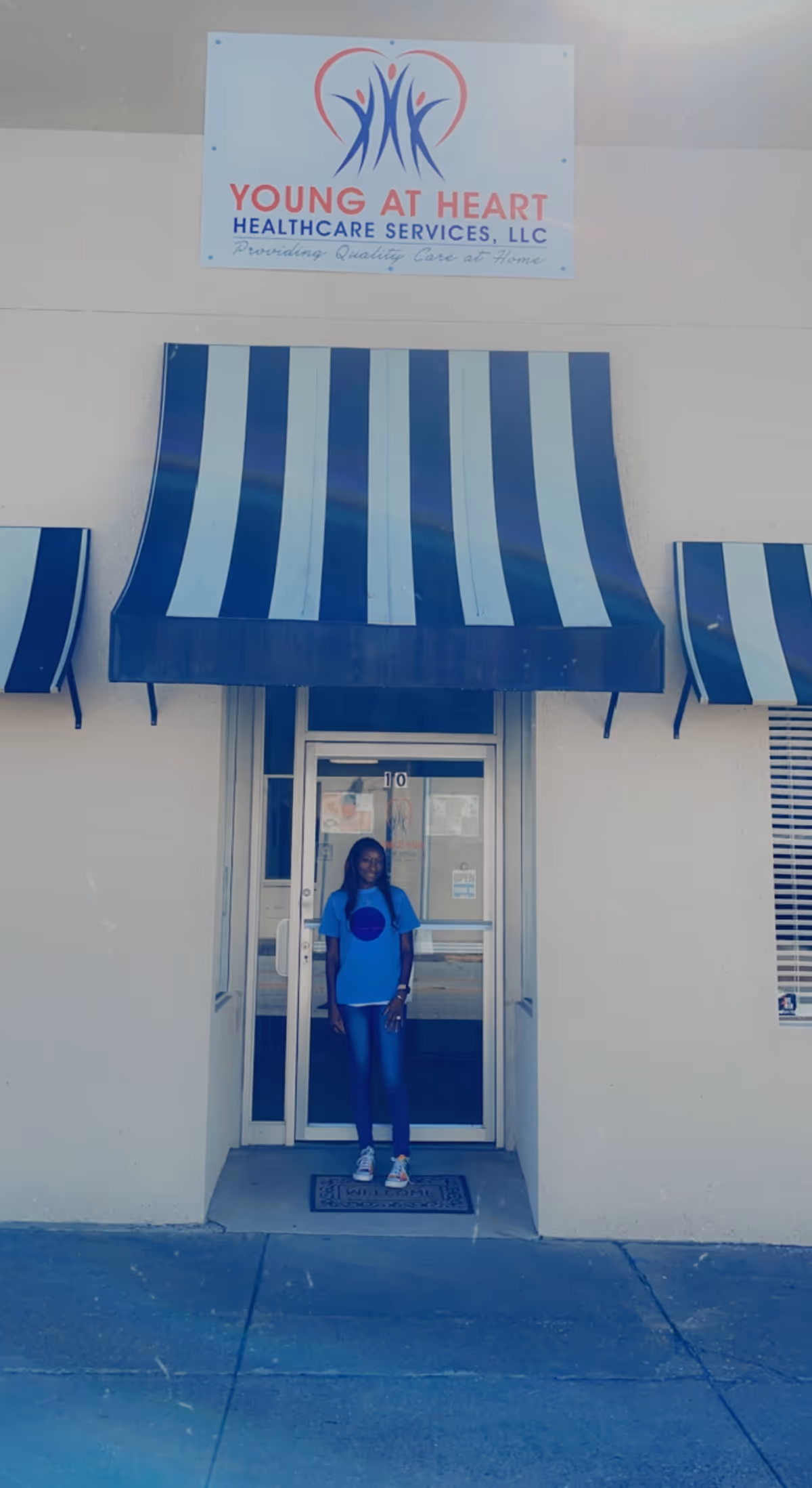 Front entrance of Young at Heart Healthcare Services with striped blue awning and a person standing.