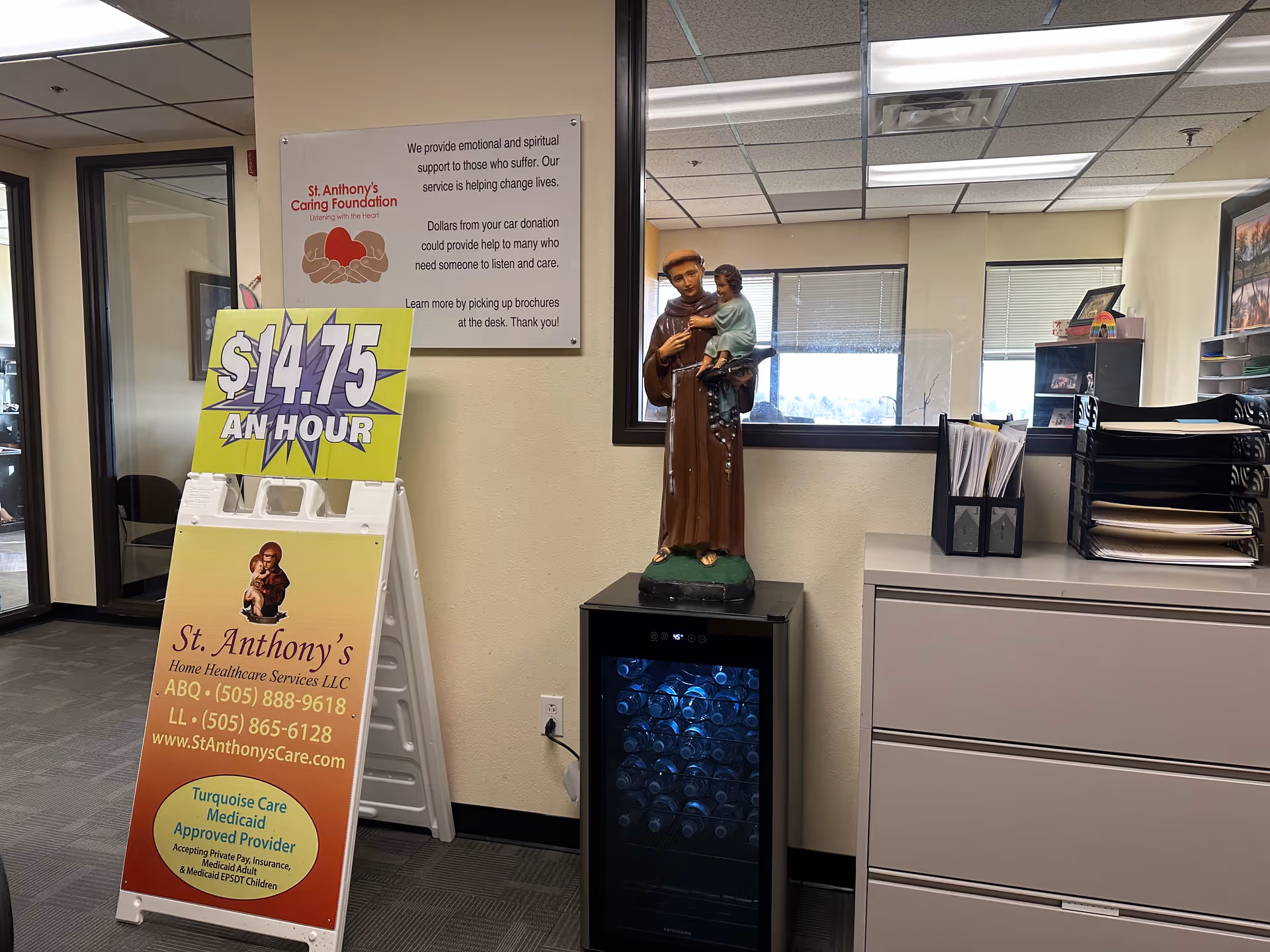 Interior reception area with a Saint Anthony statue, signs, and a filing cabinet.
