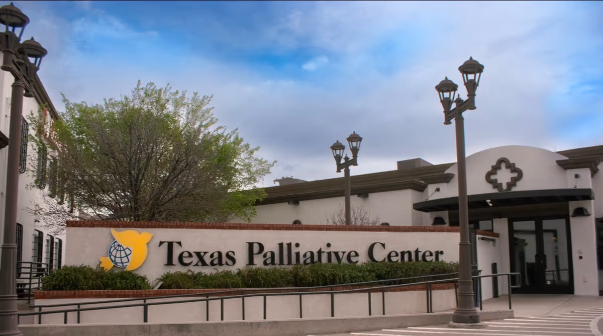 Exterior view of Texas Palliative Center with sign, trees, and decorative street lamps.