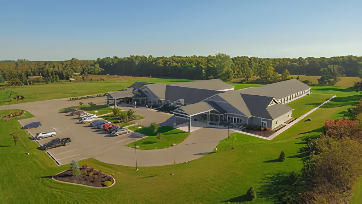 Aerial view of a single-story care facility with a circular driveway, parking lot, and surrounding lawns and trees.