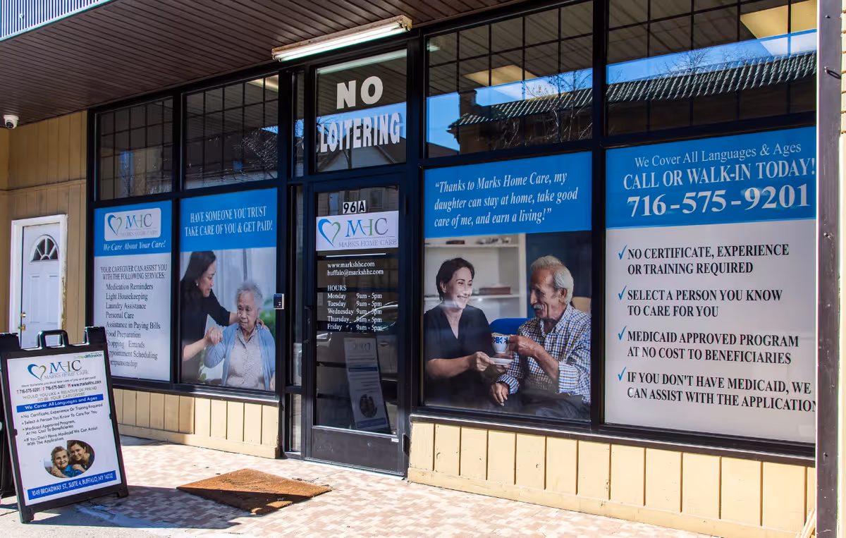 Exterior storefront of Marks Home Care Agency with large windows and promotional posters.