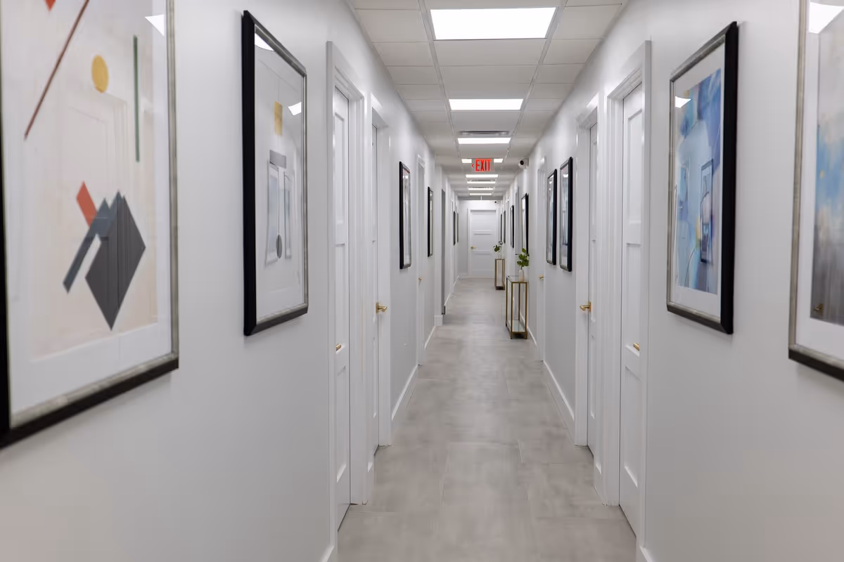 A bright, clean hallway in a senior living facility with framed artwork along walls.
