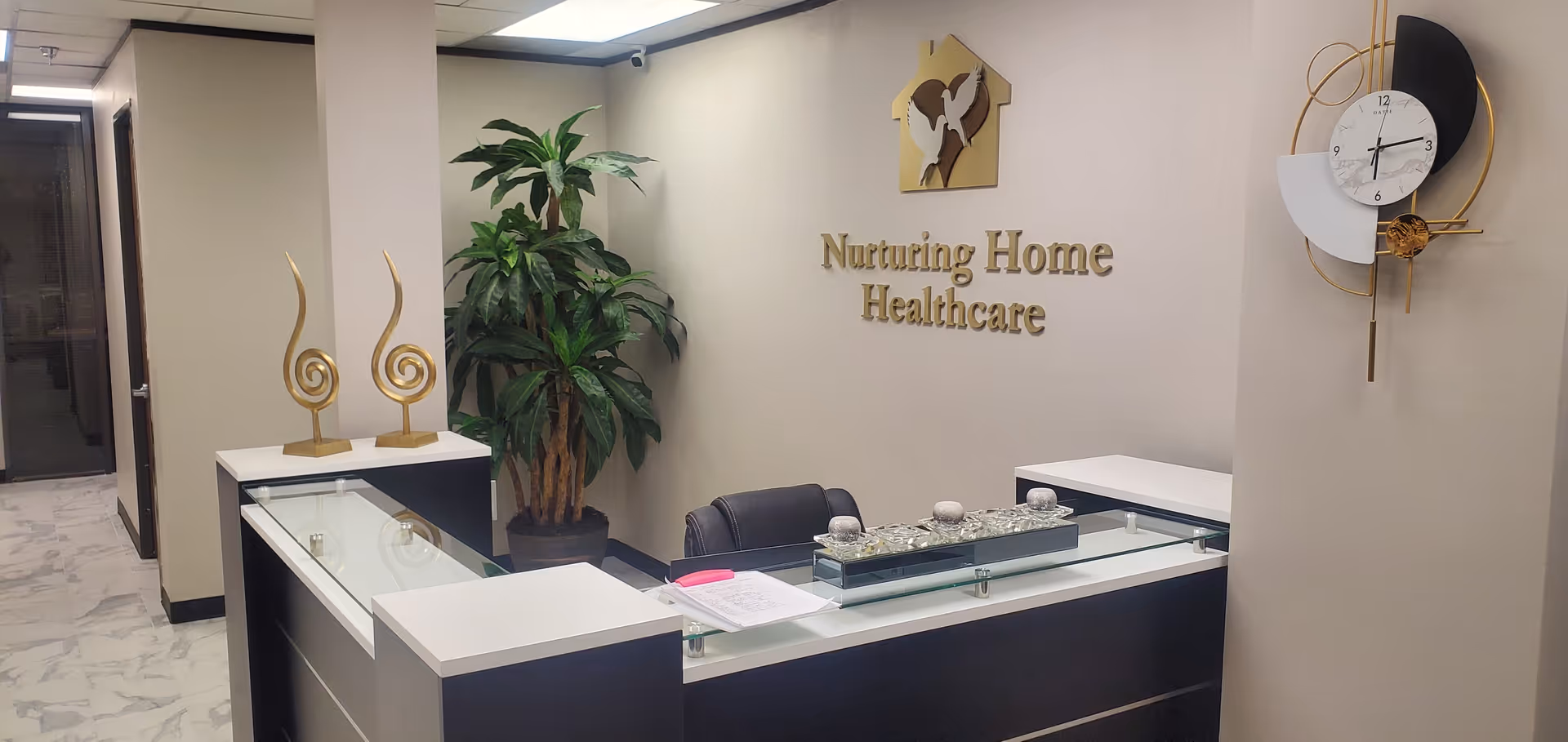 Reception desk in a modern facility lobby with plants and 'Nurturing Home Healthcare' sign.