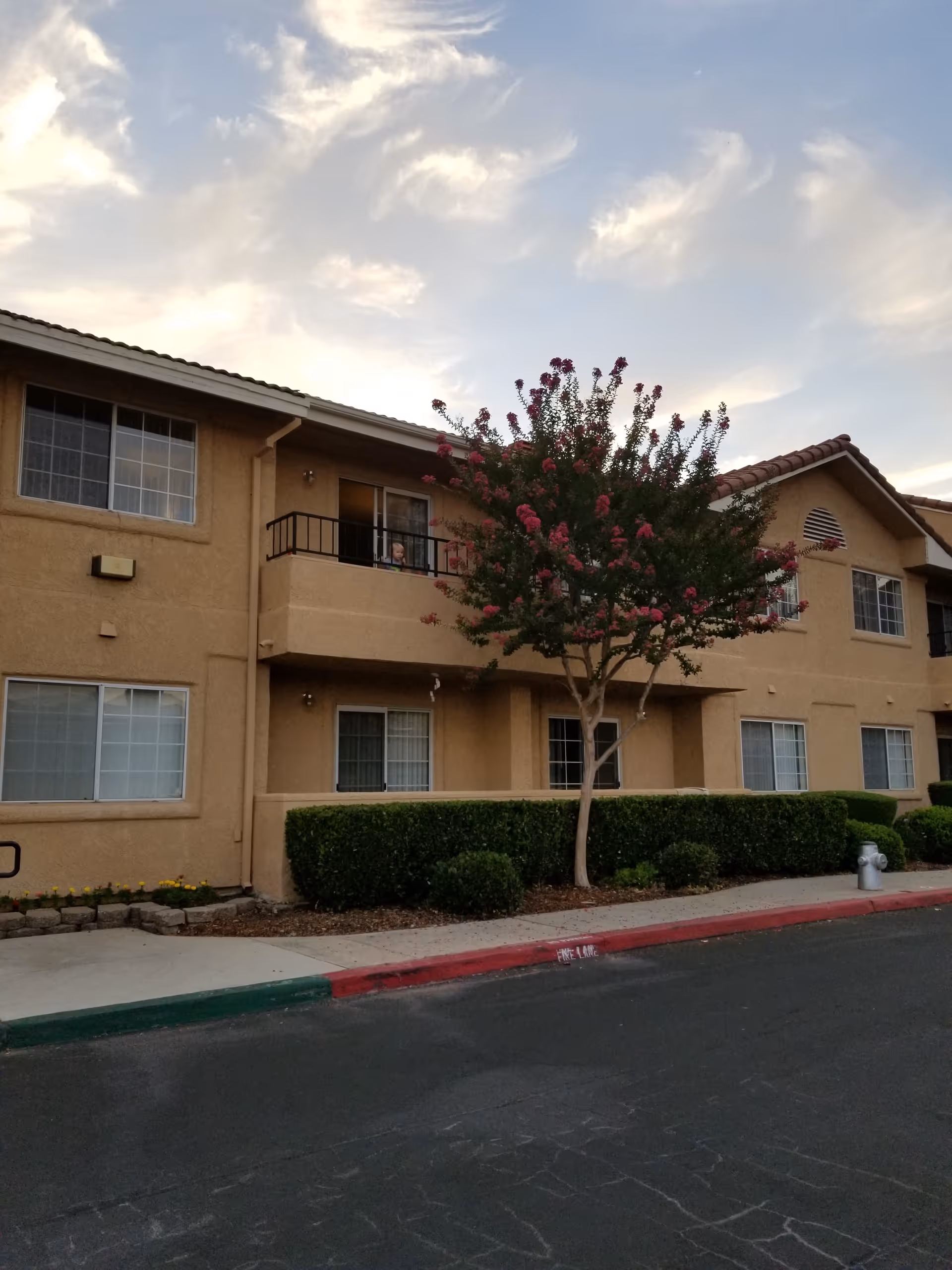 Exterior view of Fresno Senior Living building with balconies, trees, and well-kept landscaping.